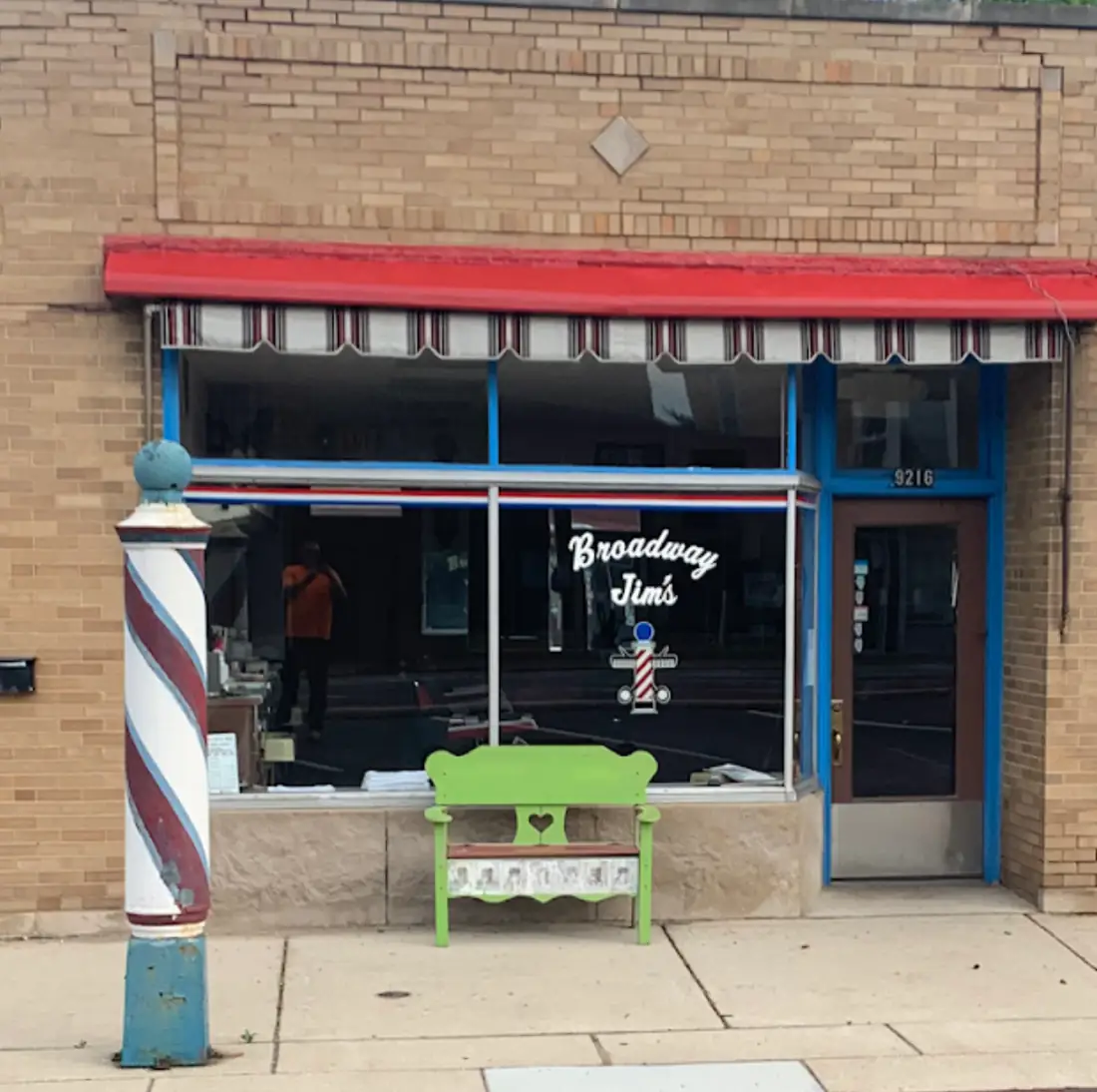 Broadway Jim’s storefront on Broadway Ave with the red awning and barber pole